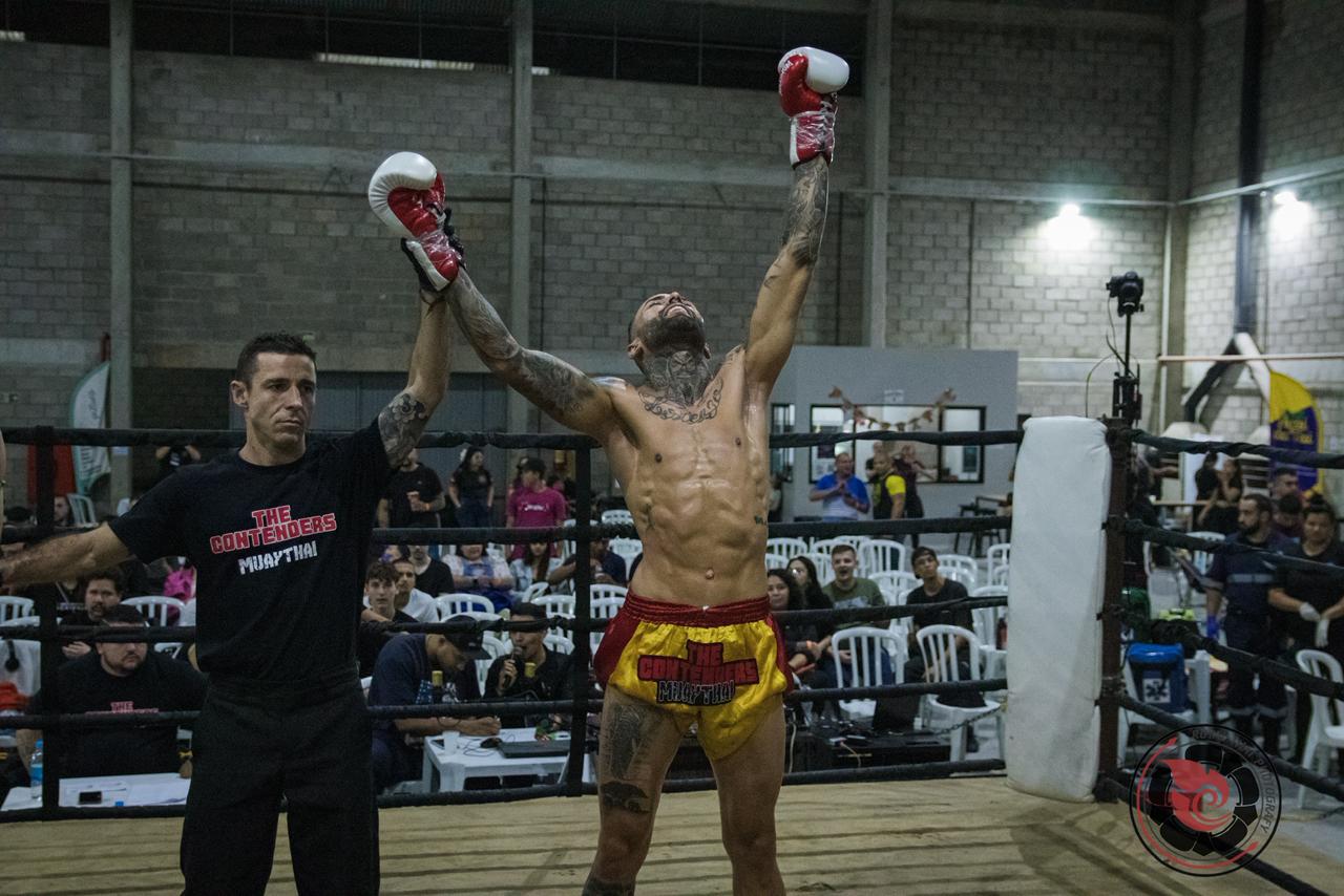 Rafael Martens com os braços erguidos após vitória, com o árbitro no ringue