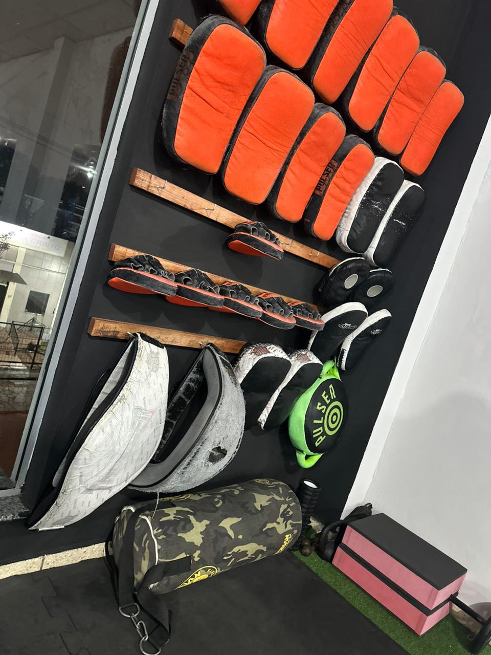 Parede com aparadores, luvas, escudos e equipamentos de Muay Thai